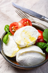 Soft white Italian cheese Mozzarella buffalo served with fresh tomato and green basil leaves