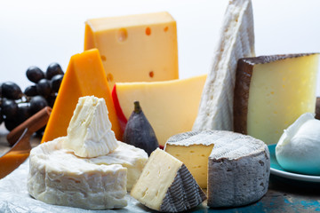 Famous European cheeses in assortment, Dutch red ball Edam and old cheeses with holes, Spanish Manchego cheese, French soft Brie and Camembert, English cheddar and Italian mozzarella buffalo