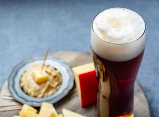 Delicious mix, dark Belgian beer and pieces of hard cheese with mustard