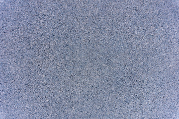 A close-up of a surface of treated grey granite rock plate. A fragment of a stone wall decoration. Texture of bright grey granite facing material.