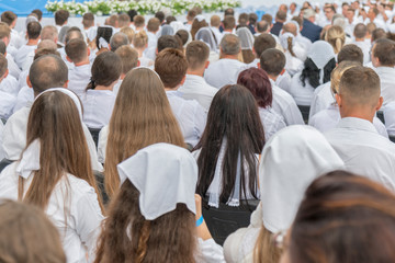 Men and women in white clothes prepare to receive water baptism.