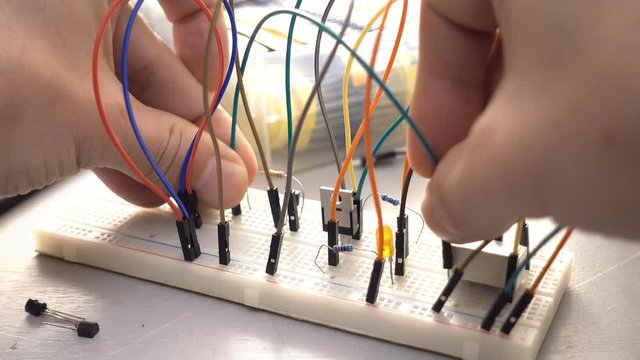 Maker, student or electronics engineer developing prototype electronics circuit on breadboard