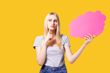 Young beautiful woman wearing white t-shirt and mom jeans, holding blank speech bubble with copy space for text. Attractive blonde female with empty message box. Grey isolated background.