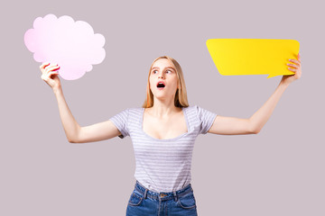 Young beautiful woman wearing white t-shirt and mom jeans, holding blank speech bubble with copy space for text. Attractive blonde female with empty message box. Grey isolated background.