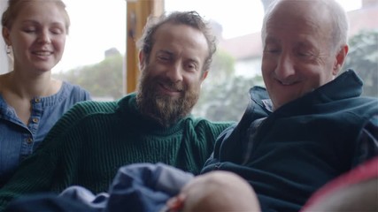 Parents and grandfather look lovingly at the new addition to the family, a baby boy