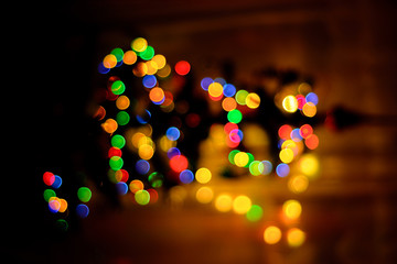 A colored bokeh in the background blurs a Christmas tree
