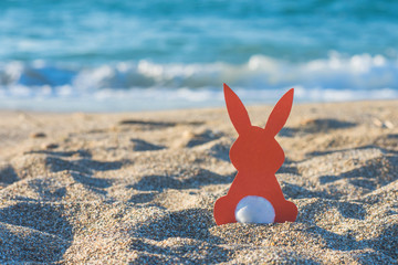 Creative easter concept photo of red paper bunny on the sand on the beach at sunset. Concept of Easter celebrations in tropical countries. - 241304338