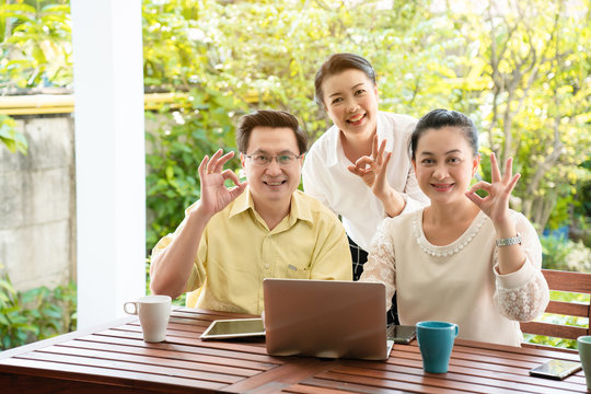 Group Asian elderly men and women are living the tablet and laptop happily with a smile of friendship. By searching for health care information tourism And investment after retirement. Elderly concept