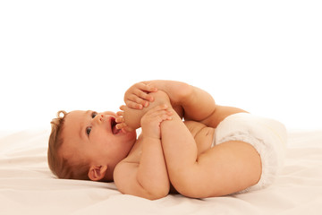 Fototapeta na wymiar Hapy baby boy in playing on bed isolated over white