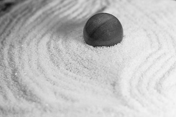 Une grosse bille enfoncée dans dans le sable blanc d'un jardin zen