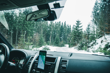 view from car dashboard with phone with navigation off road.