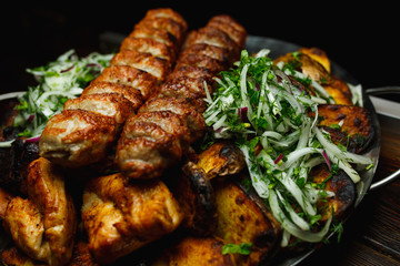 Shish kebab, kebab on a dark background. Different fried meat in plate