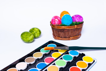 Decorating colorful easter eggs with a paintbrush on white background