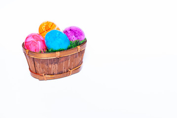 A basket filled with green grass and colorful easter eggs on white background with copy space