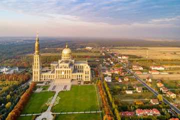 Fototapeta na wymiar Village Lichen in Poland with Sanctuary and Basilica of our Lady of Licheń. The biggest church in Poland, one of the largest in the World. Famous pilgrimage site. Aerial view in fall. Sunset light