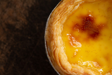 Egg tarts in aluminum foil cup on wood table,  traditional Portuguese dessert served in coffee shop