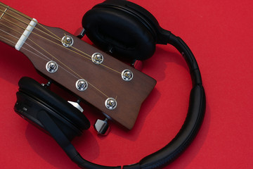 the upper part of the guitar neck, headphones on a red background.