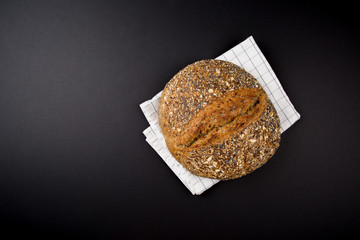 Bread, Fresh Healthy Bread covered with Seeds on kitchen towel, black background, copy space