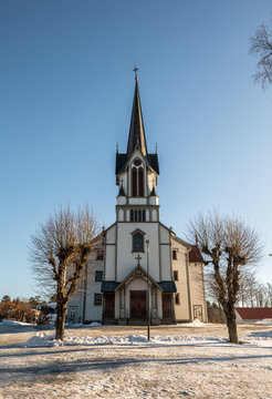 Bamble Church, large wooden church buildt in 1845. Winter, snow, blue sky. Front view. Vertical image.