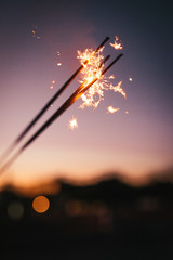 A closeup of fireworks and sparklers during an evening sunset