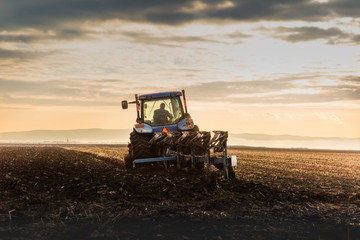 Fototapeta premium Tractor Plowing in dusk