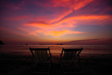 Couple of sun loungers on the beach during twilight.