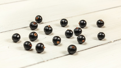 Naklejka na ściany i meble Blackcurrants (Ribes nigrum) spilled on white boards desk