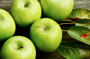 Health Benefits Of Green Apples. Green apples with leaf on wooden background.