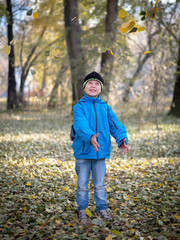 happy boy throws leaves in autumn Park