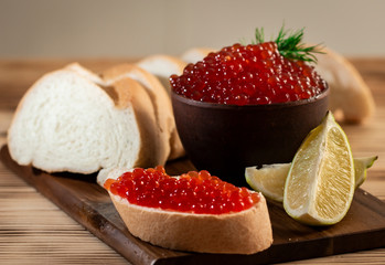 red caviar in a ceramic dish on a wooden background in a rustic style with space for text