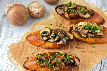 Champignon or brown cap mushroom Crostini on brown paper and wooden board.