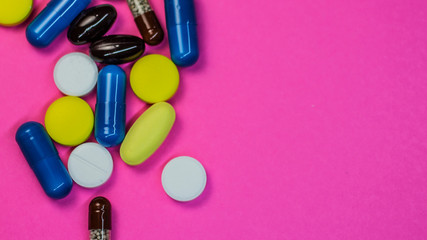 Various medical pills on pink background