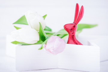 Happy Easter. Easter bunny and delicate tulips on a white background. Copy space
