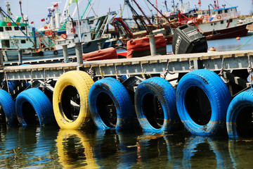 Fototapeta na wymiar Old Yellow Tire Barrier on a harbor