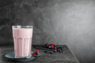 Glass of protein shake and berries on table against grey background. Space for text