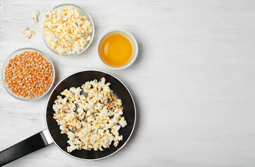 Composition with popcorn, oil and space for text on wooden table, flat lay
