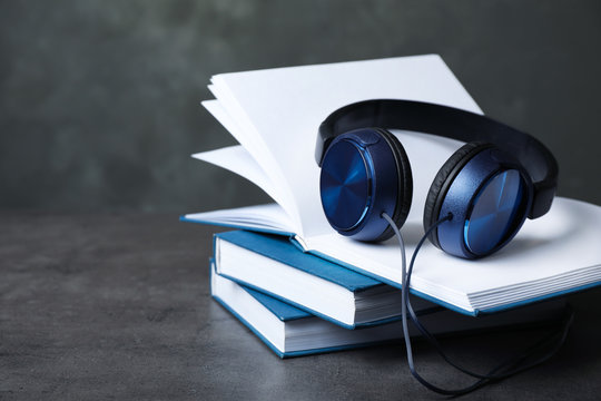 Modern headphones with hardcover books on grey table. Space for text