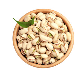 Organic pistachio nuts and leaves in wooden bowl isolated on white, top view