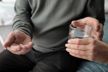 Fototapeta premium Young woman giving water to senior man with pills, closeup