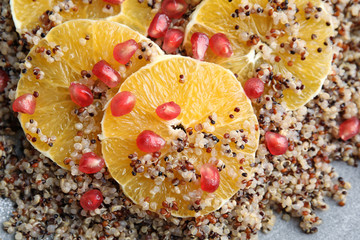 Quinoa porridge with orange and pomegranate seeds on plate as background, top view