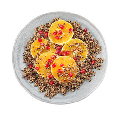 Plate of quinoa porridge with orange and pomegranate seeds on white background, top view