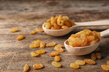 Spoons with raisins on wooden table. Dried fruit as healthy snack