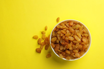 Bowl with raisins and space for text on color background, top view. Dried fruit as healthy snack
