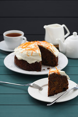 Black tea and chocolate cake with cream cheese and orange peel on dark blue background