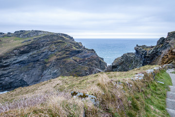 rocks by the sea, where only the grass grows; narrow tourist path on the rocky coast; sea landscape with rocks and sea