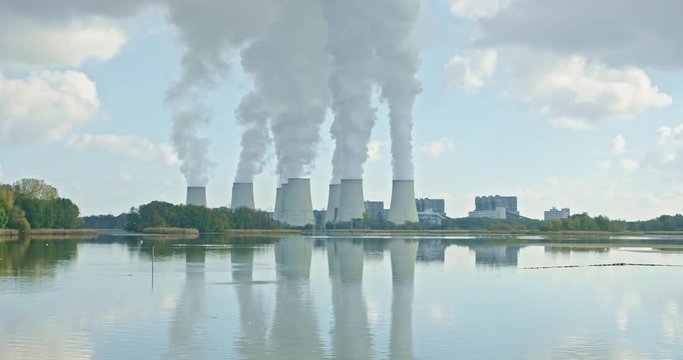 A power plant is reflected in a lake, carp fish jumping out of the water, birds are pulling their circles. It is an almost idyllic picture.