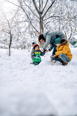 Fototapeta na wymiar Mother helping son putting on snow gloves