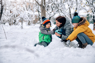 Mother helping son putting on snow gloves