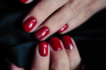 Gorgeous manicure, clssic red color nail polish, closeup photo. Female hands over dark fur background