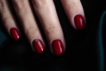 Gorgeous manicure, clssic red color nail polish, closeup photo. Female hands over dark fur background